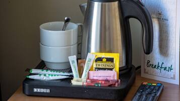 A breakfast tray with a coffee pot, cups, and food packets on a table.