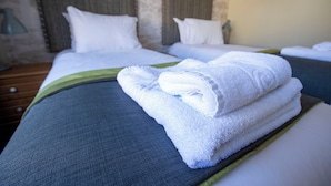 Une chambre d’hôtel avec deux lits, chacun agrémenté de draps et d’oreillers blancs, et une touche de vert sur la couvre-lit.