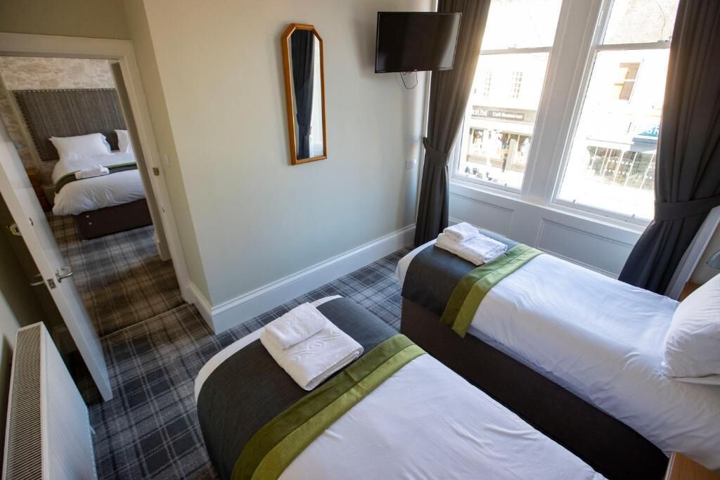 Une chambre d’hôtel avec deux lits, un téléviseur à écran plat, un miroir et une fenêtre donnant sur la rue.