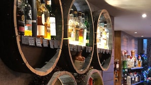 Un espace bar doté de plusieurs étagères en bois où sont exposées différentes bouteilles d’alcool.