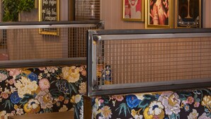 L’intérieur d’un restaurant présente des banquettes à motifs floraux, des suspensions décoratives et des œuvres d’art encadrées accrochées aux murs.