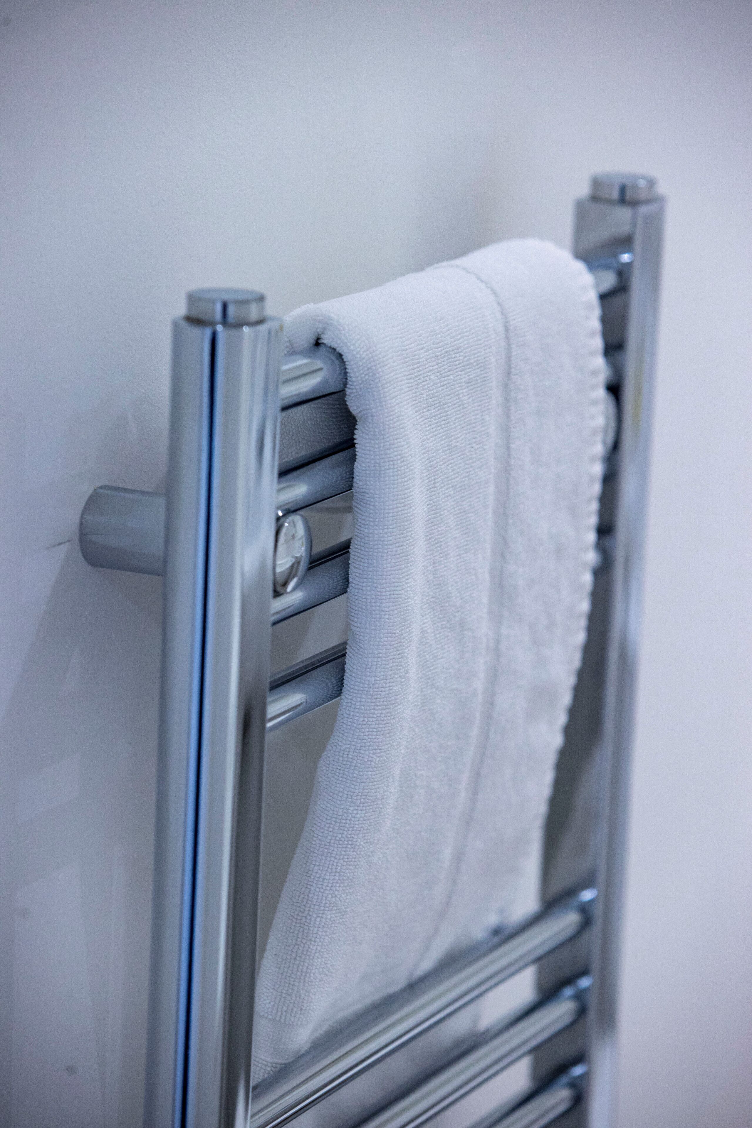 A metallic towel rail with a white towel hanging on it.
