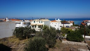 A coastal residential area with houses, some with red-tiled roofs, and a clear view of the sea. - Yialos Studios (Agistri)