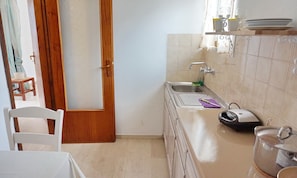 Una cocina compacta con un lavamanos, una tetera y una pequeña encimera.