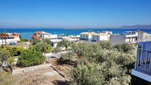 A coastal residential area with houses, some with solar panels, and a clear view of the sea. - Yialos Studios (Agistri)