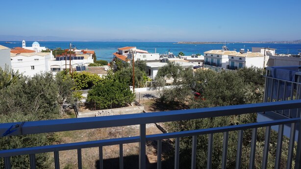 A coastal residential area with white buildings, a clear blue sky, and a view of the sea. - Yialos Studios (Agistri)