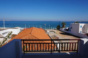 A coastal building with a red-tiled roof, white walls, and a balcony with a black railing. - Yialos Studios (Agistri)