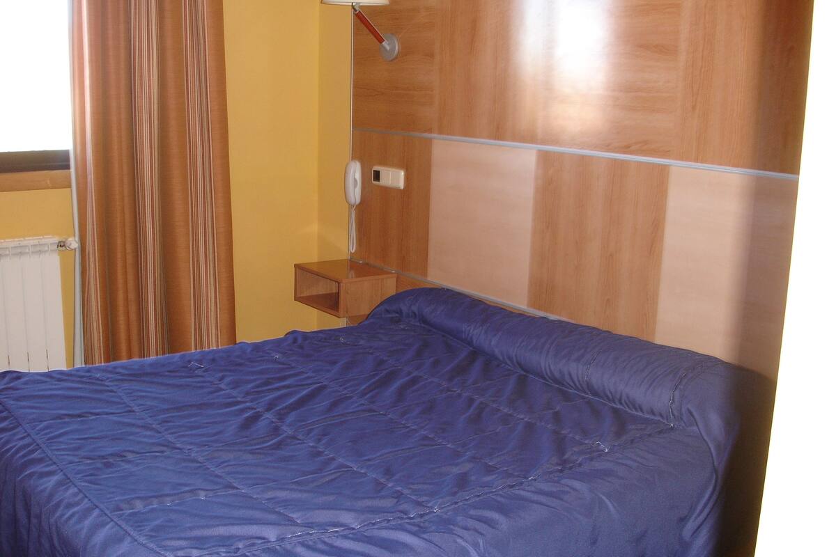 Una habitación de hotel con una cama, una mesita de noche, una lámpara y un teléfono.