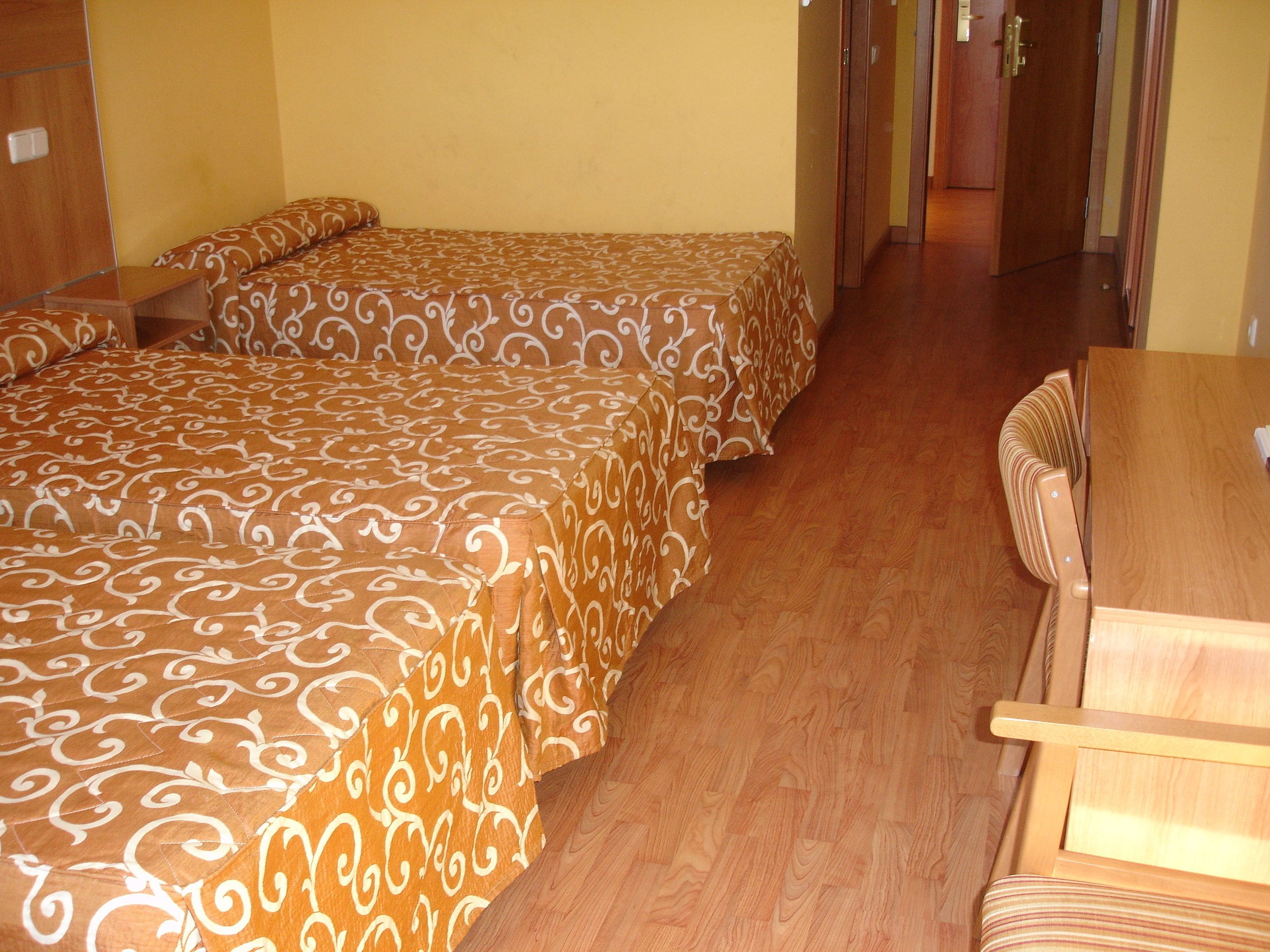 Una habitación de hotel con dos camas, una mesa de madera y una silla.