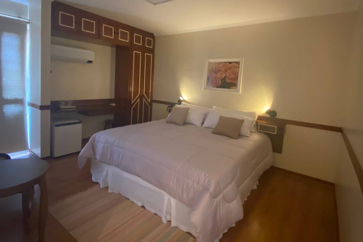 A bedroom with a bed, bedside table, and a desk with a chair.