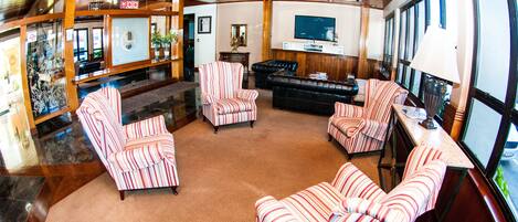 A spacious lobby with striped armchairs and sofas, a television, and a reception desk.