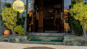 La entrada del Hotel Marques, con techo de madera, fachada de piedra y diseño de suelo en mosaico.