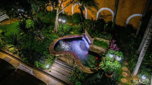 Vista aérea de un jardín ajardinado con jacuzzi, senderos de piedra y plantas en macetas.