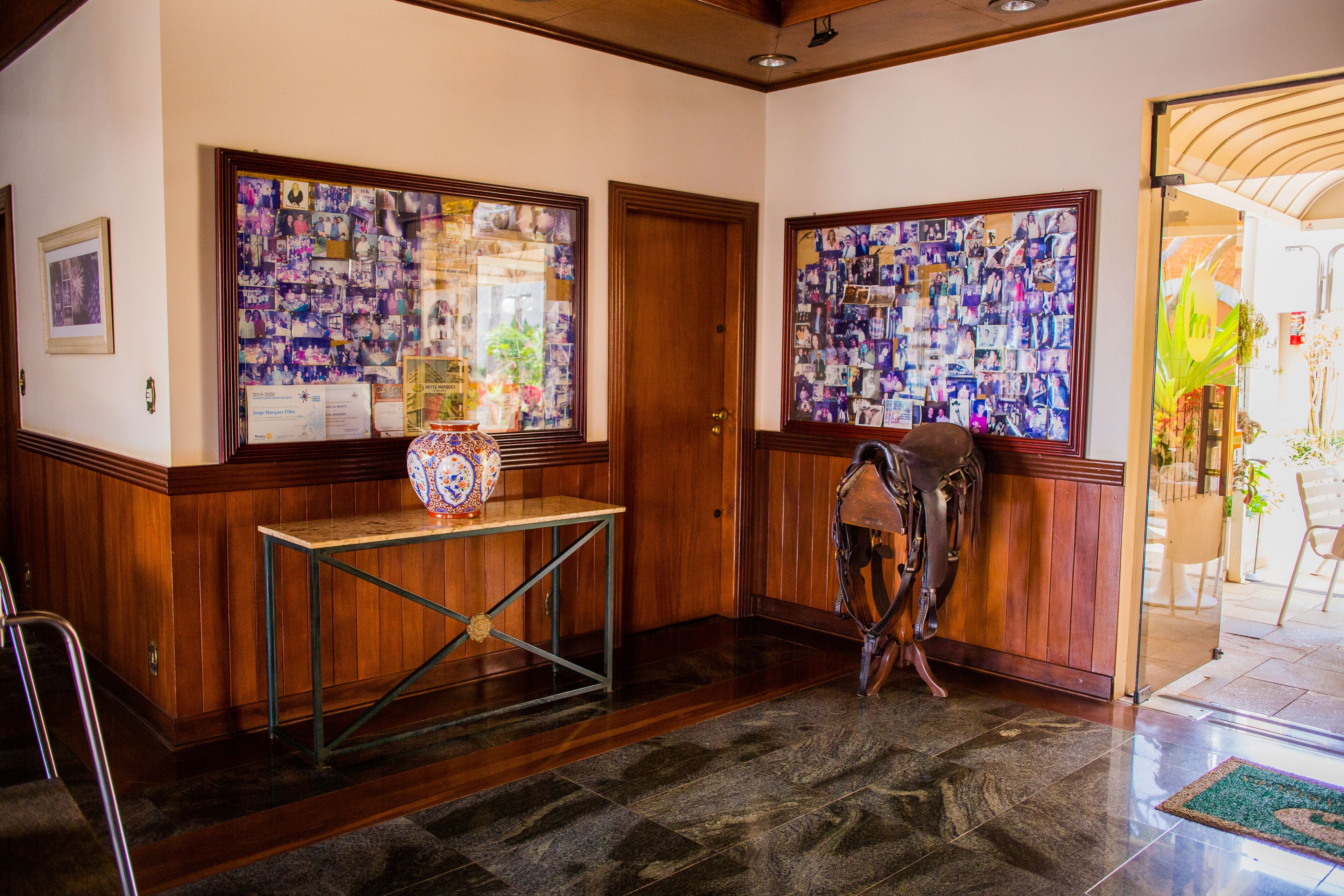 A lobby with wooden paneling, a reception desk, and two bulletin boards filled with photos.