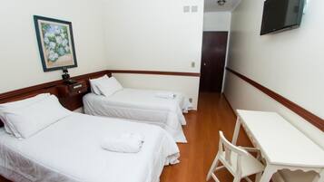A hotel room with two beds, a desk, and a painting on the wall.