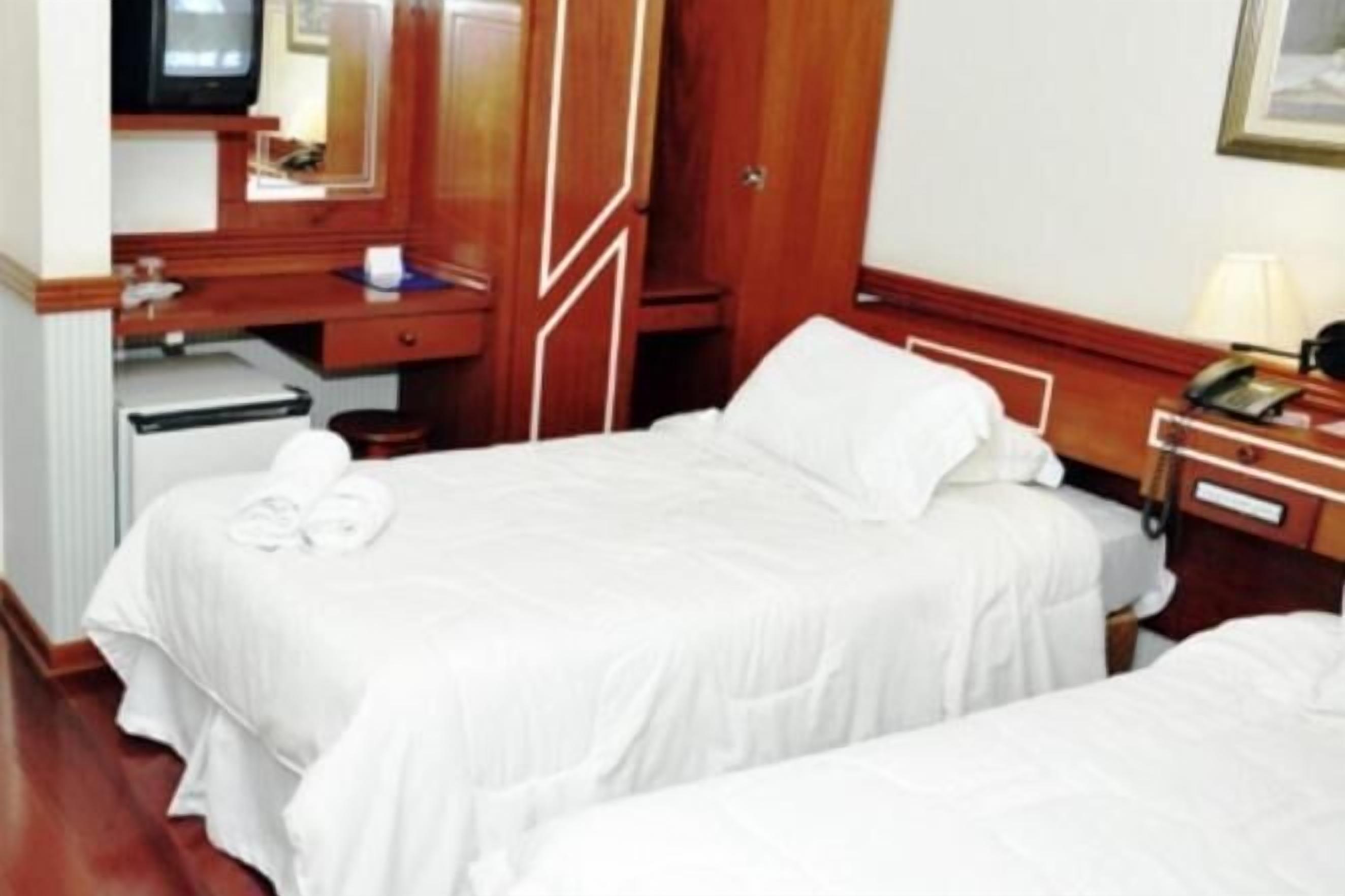Une chambre d’hôtel avec deux lits, un bureau avec un ordinateur, une télévision et un téléphone.