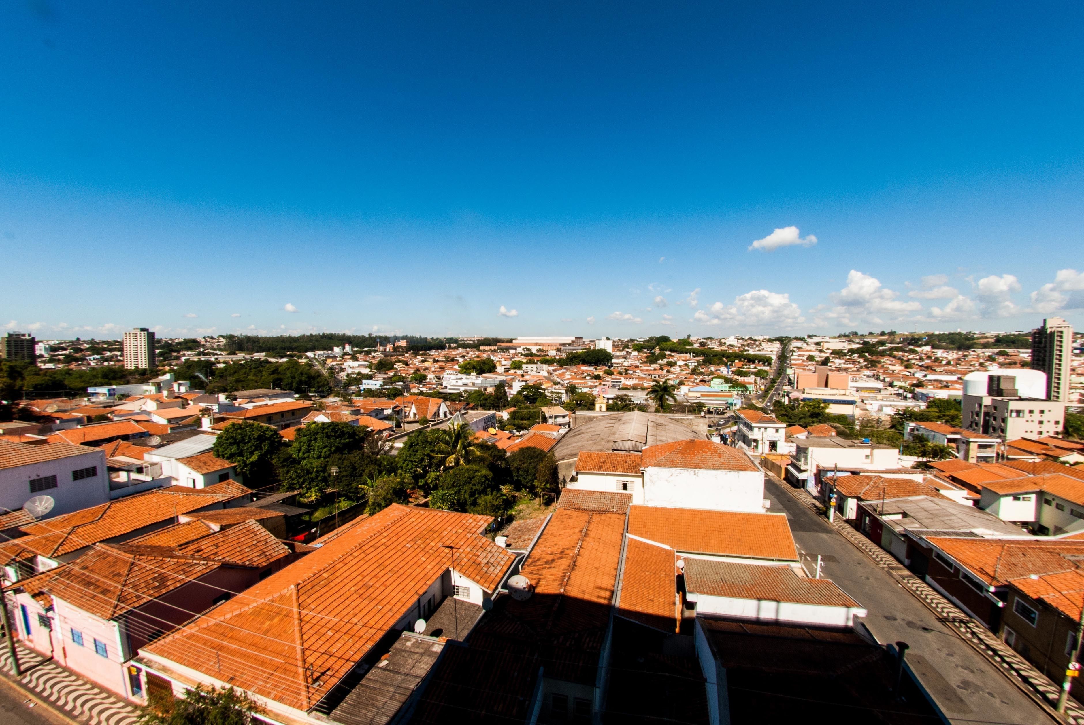 A cityscape with a mix of residential and commercial buildings, featuring red-tiled roofs and a clear blue sky.