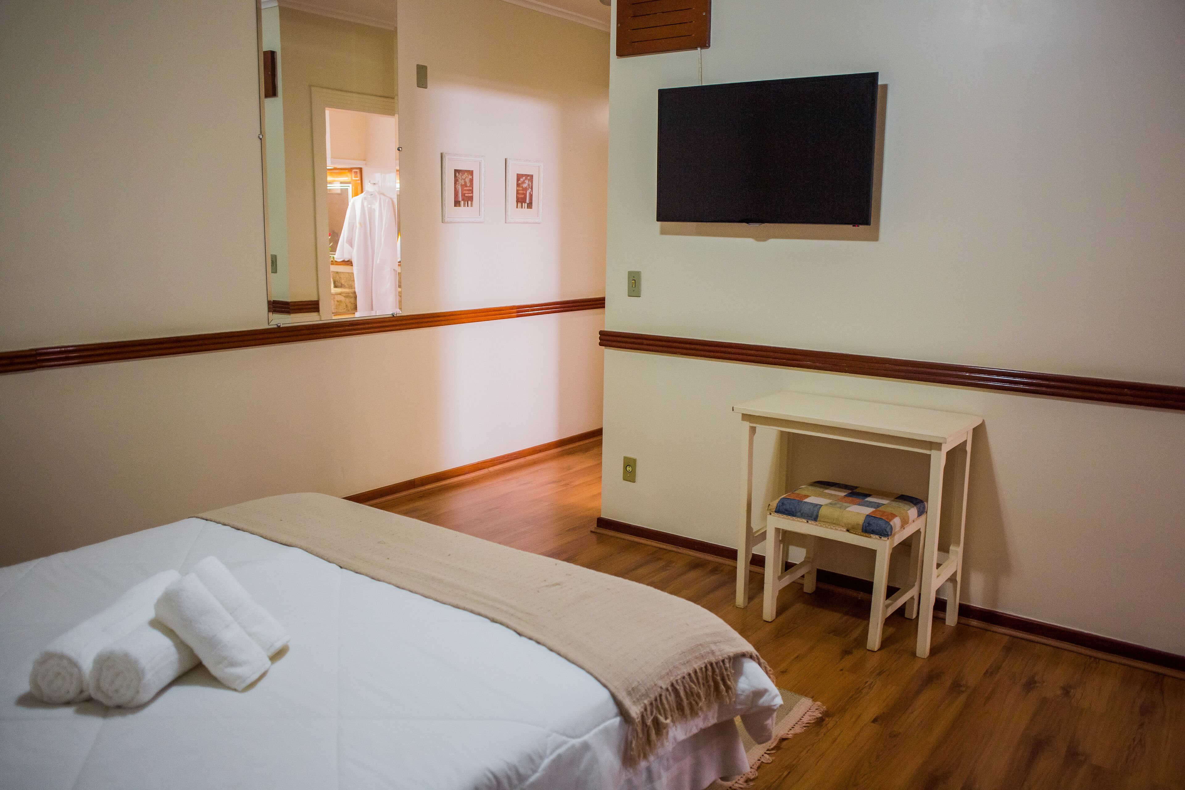 Ein Hotelzimmer mit einem Bett, einem kleinen Tisch, einem Fernseher und einem Spiegel.