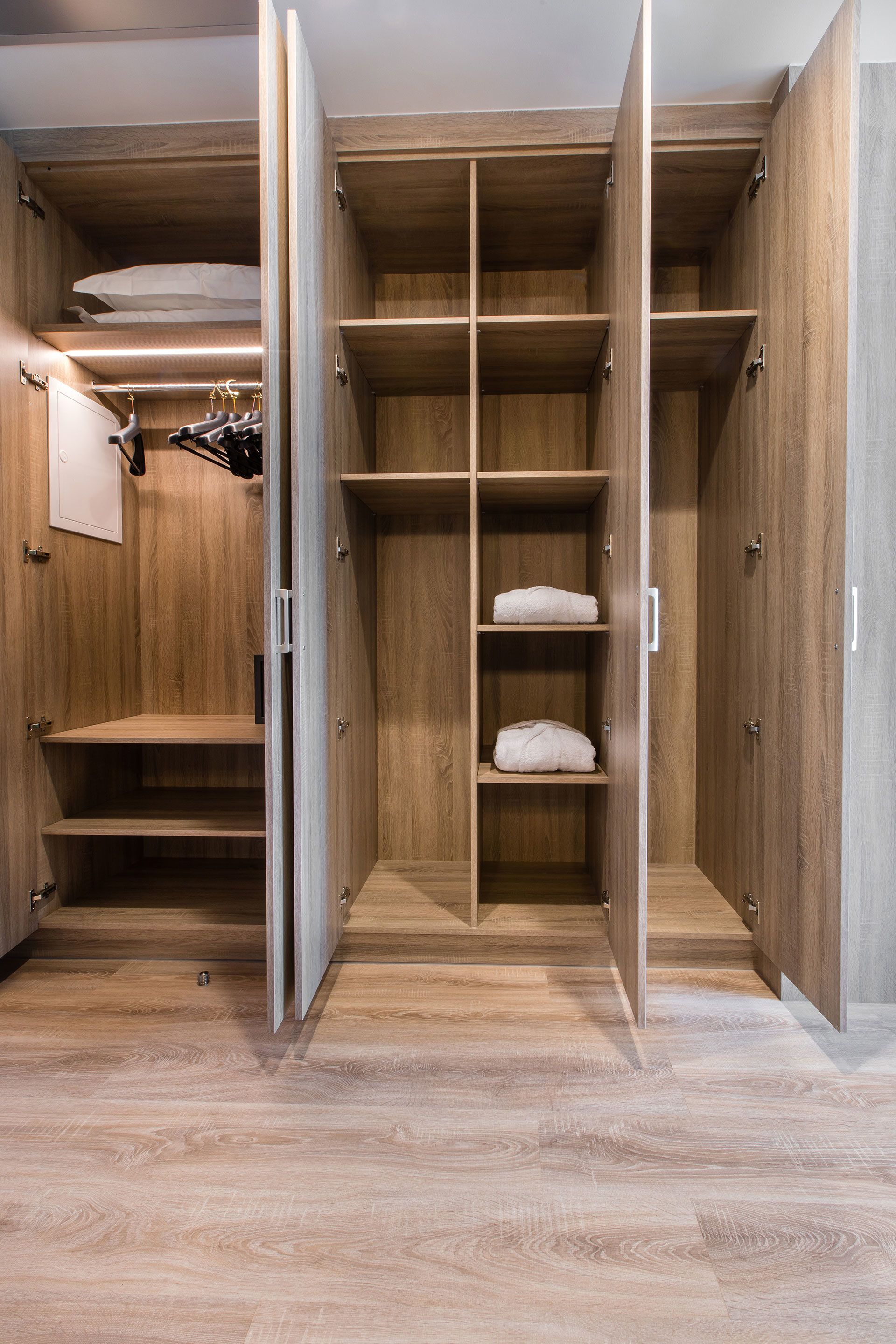 Un vestidor de madera con amplios estantes y espacio para colgar.