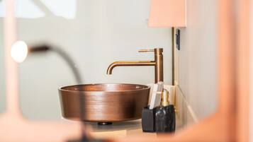 A bathroom with a copper sink, a mirror, and a black soap dispenser.