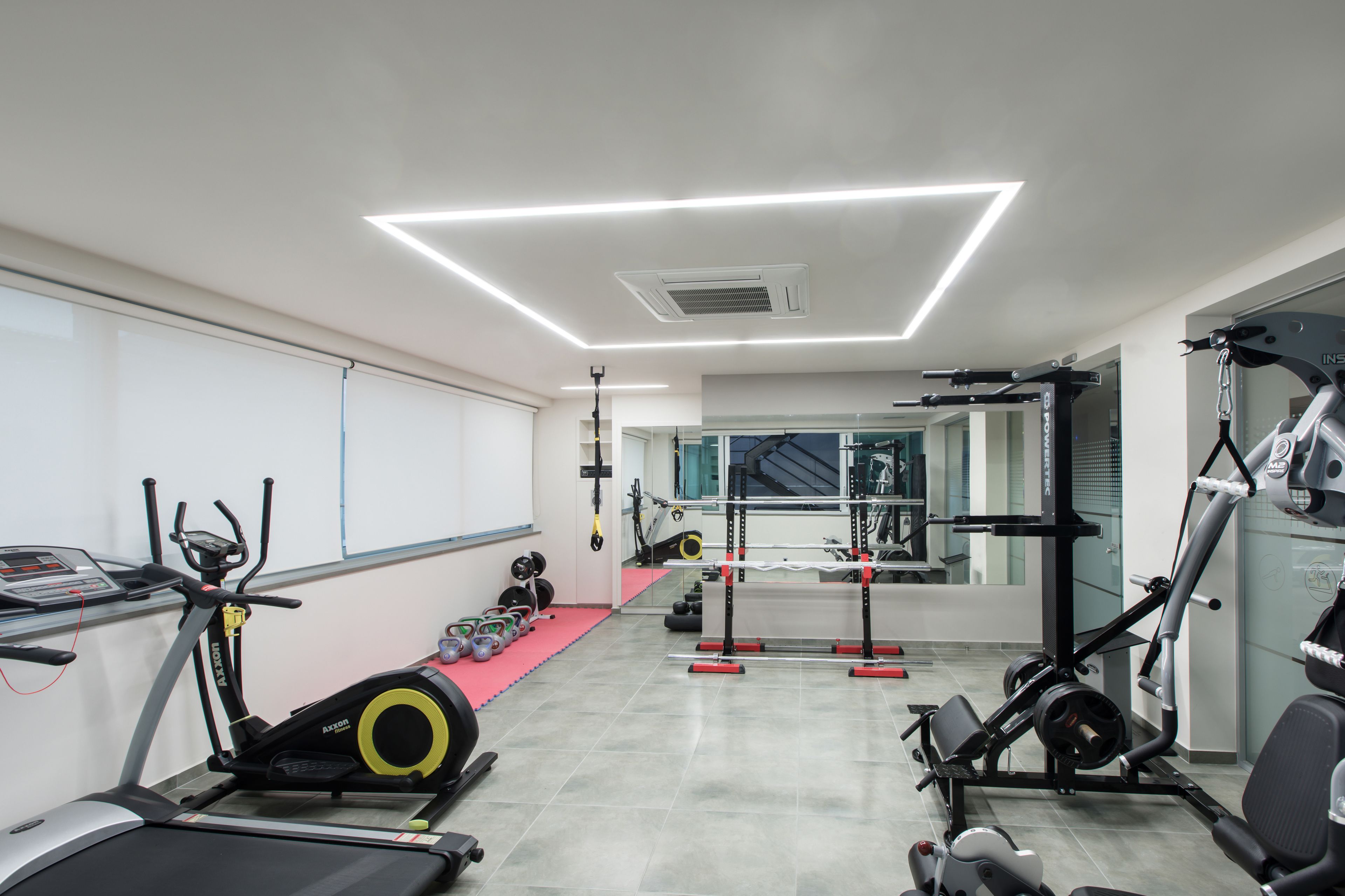 Une salle de sport moderne équipée de tapis de course, de machines de musculation et d’un support pour les exercices de squat.