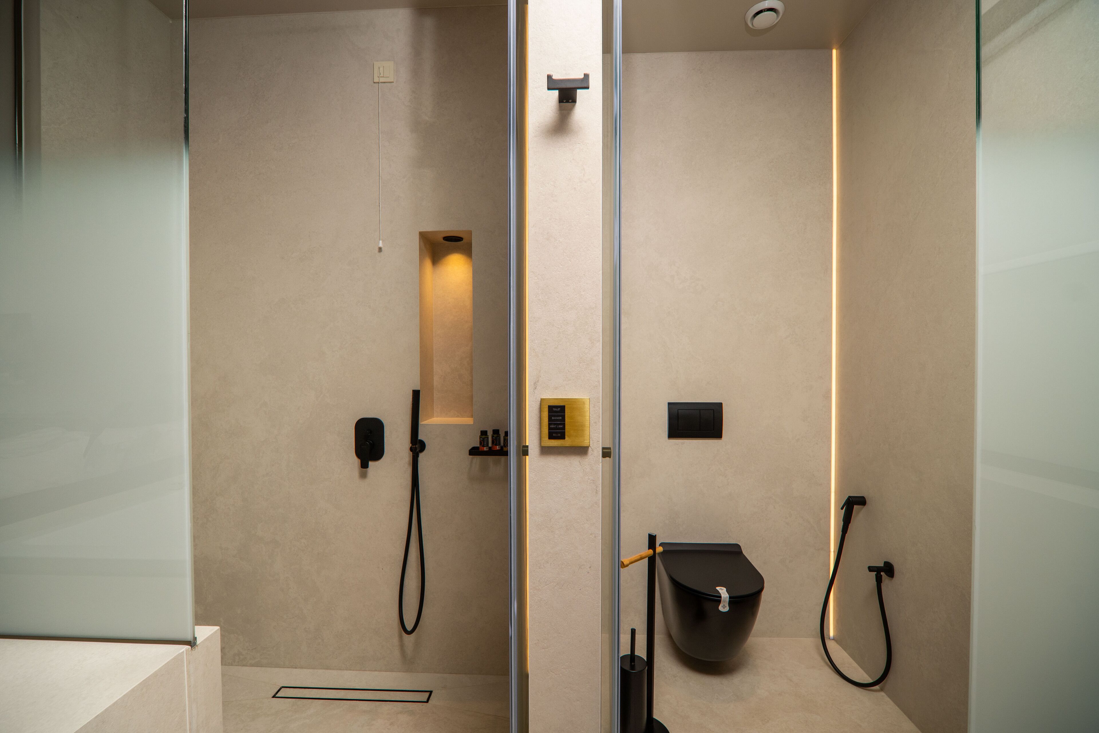 A modern bathroom with a glass partition, a shower, a toilet, and a sink.