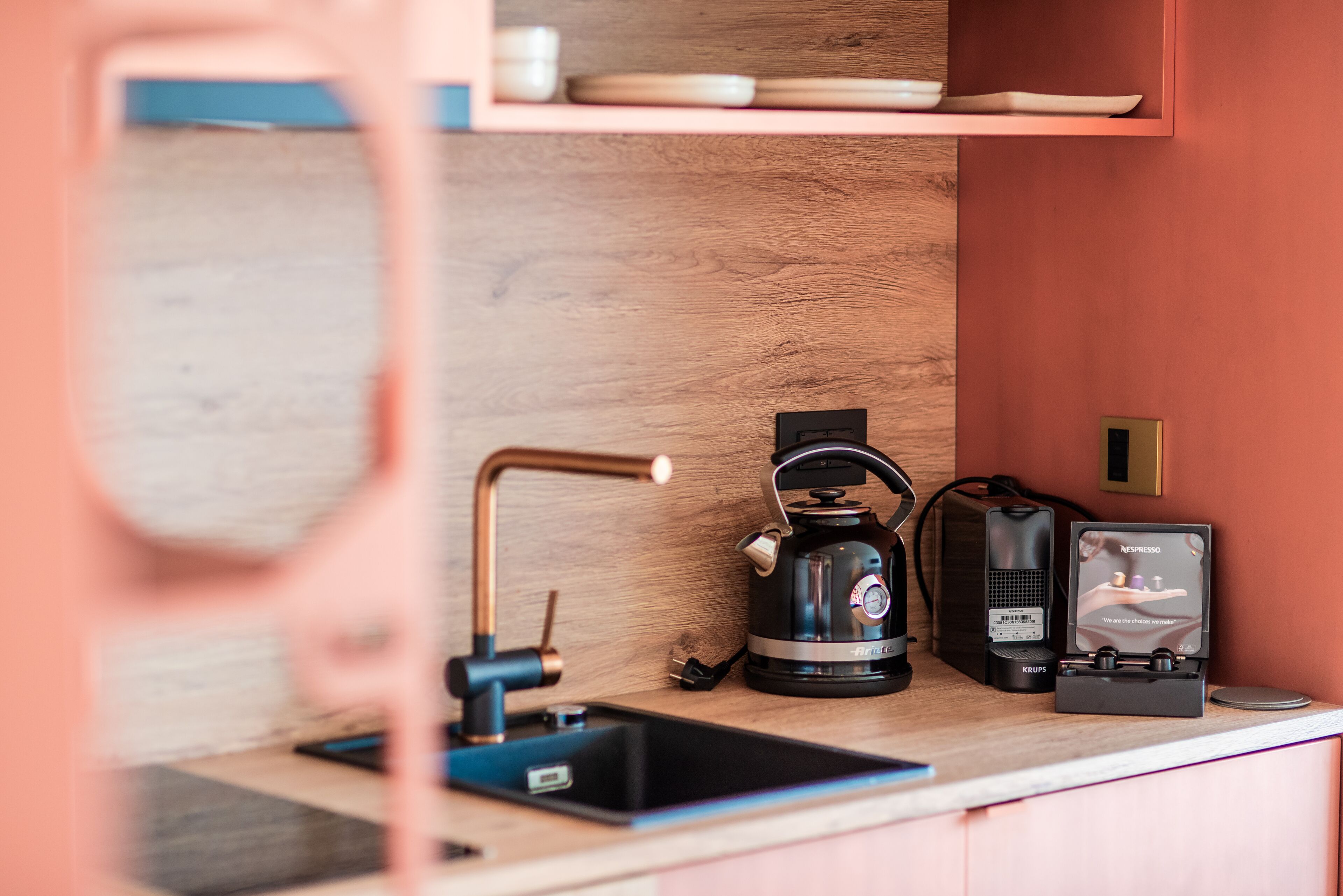 A kitchen area with a coffee machine, a kettle, and a coffee maker on the counter.