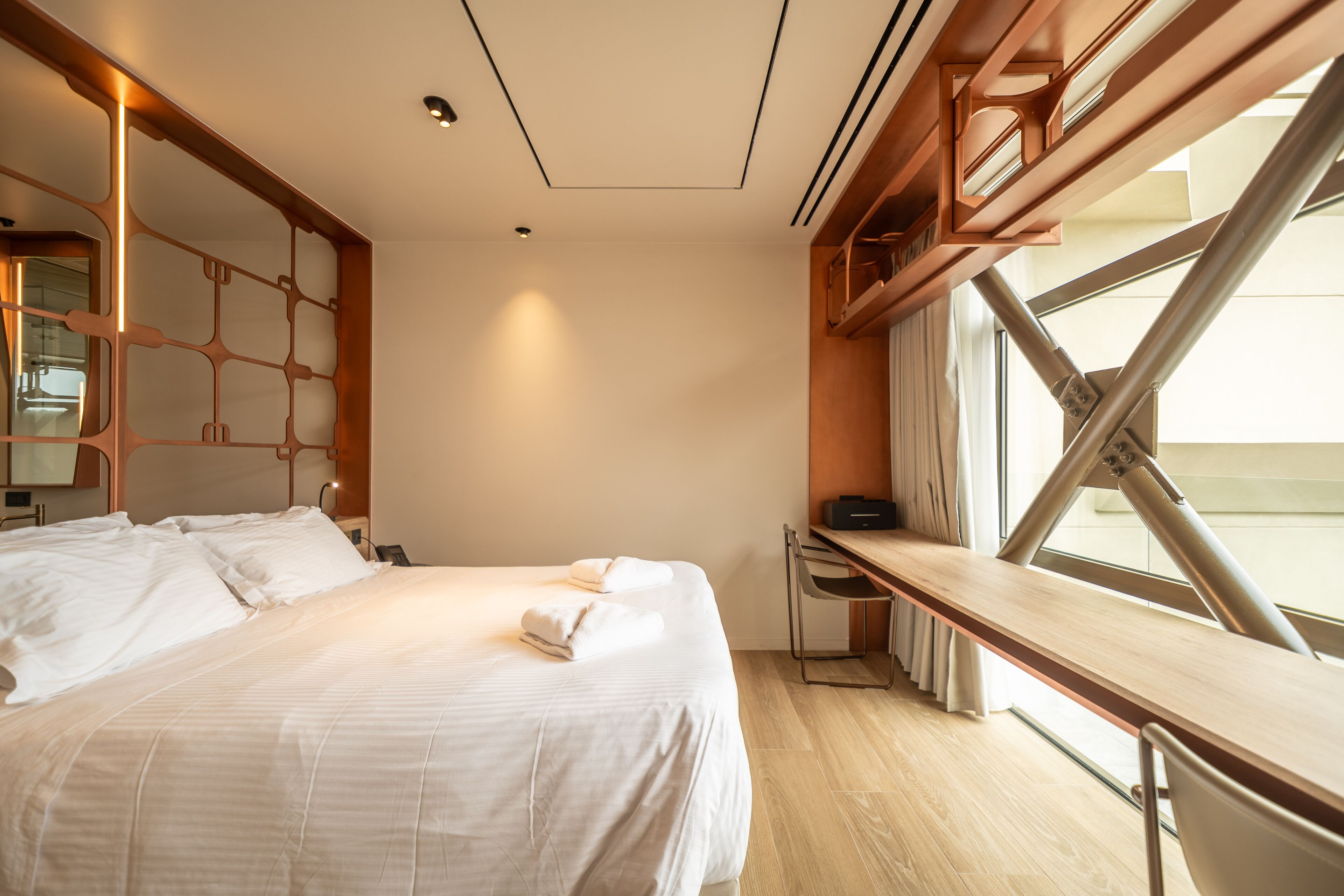 A hotel room with a bed, a desk, and a window.