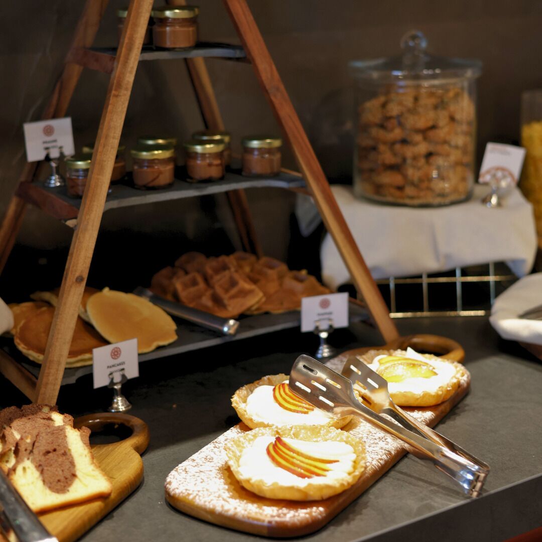 Esposizione di dolci e dessert, tra cui waffle e una torta, con un barattolo di biscotti sullo sfondo.