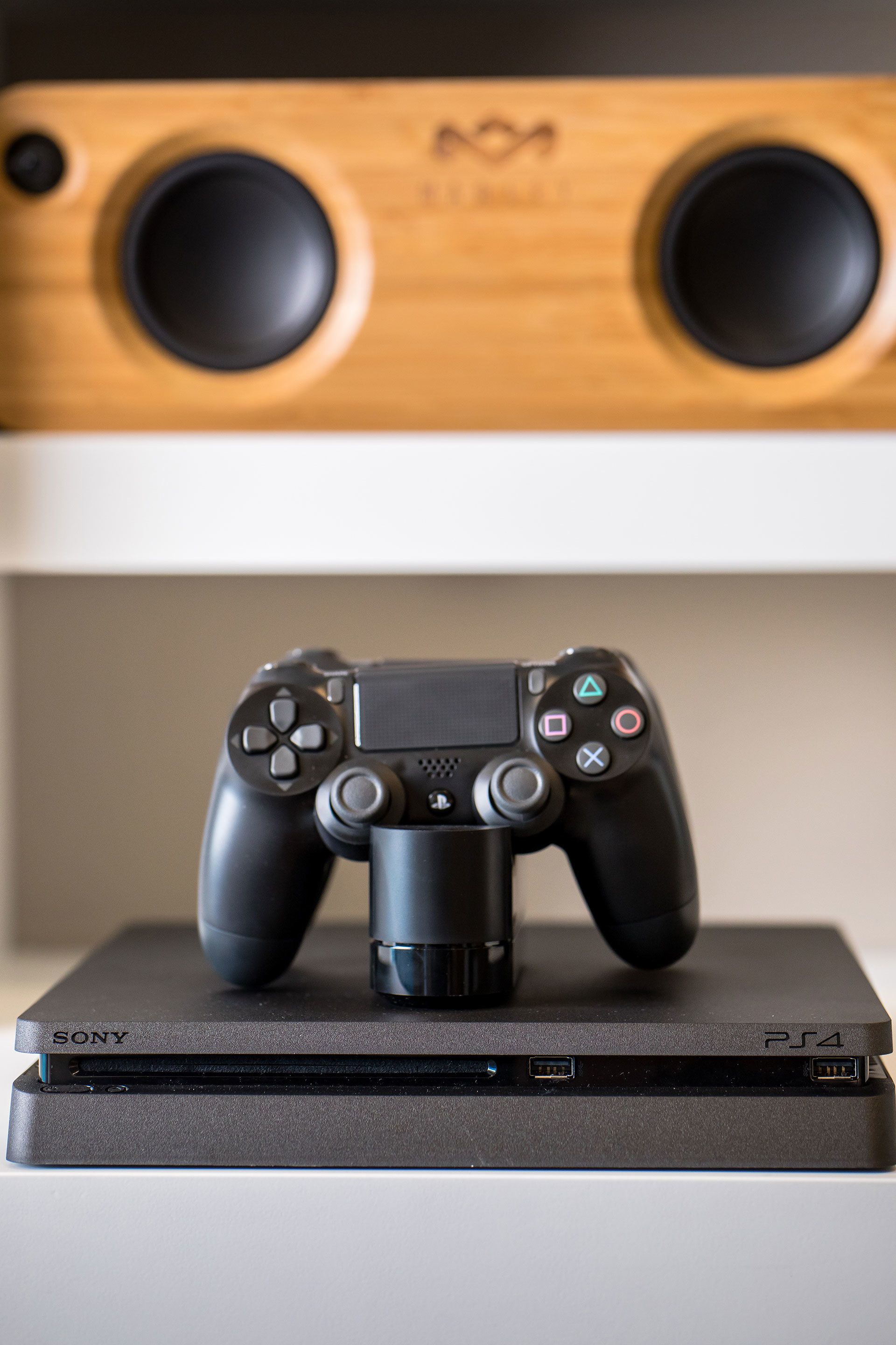 Una console PlayStation 4 con due controller sopra, posata su una superficie bianca.