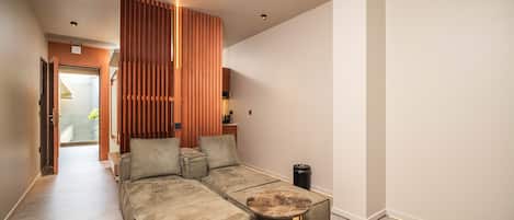 A modern living room with a sectional sofa, a round coffee table, and a wooden slatted partition.