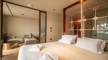 Quarto de hotel moderno com uma cama grande, uma escrivaninha, uma cadeira e um espelho.