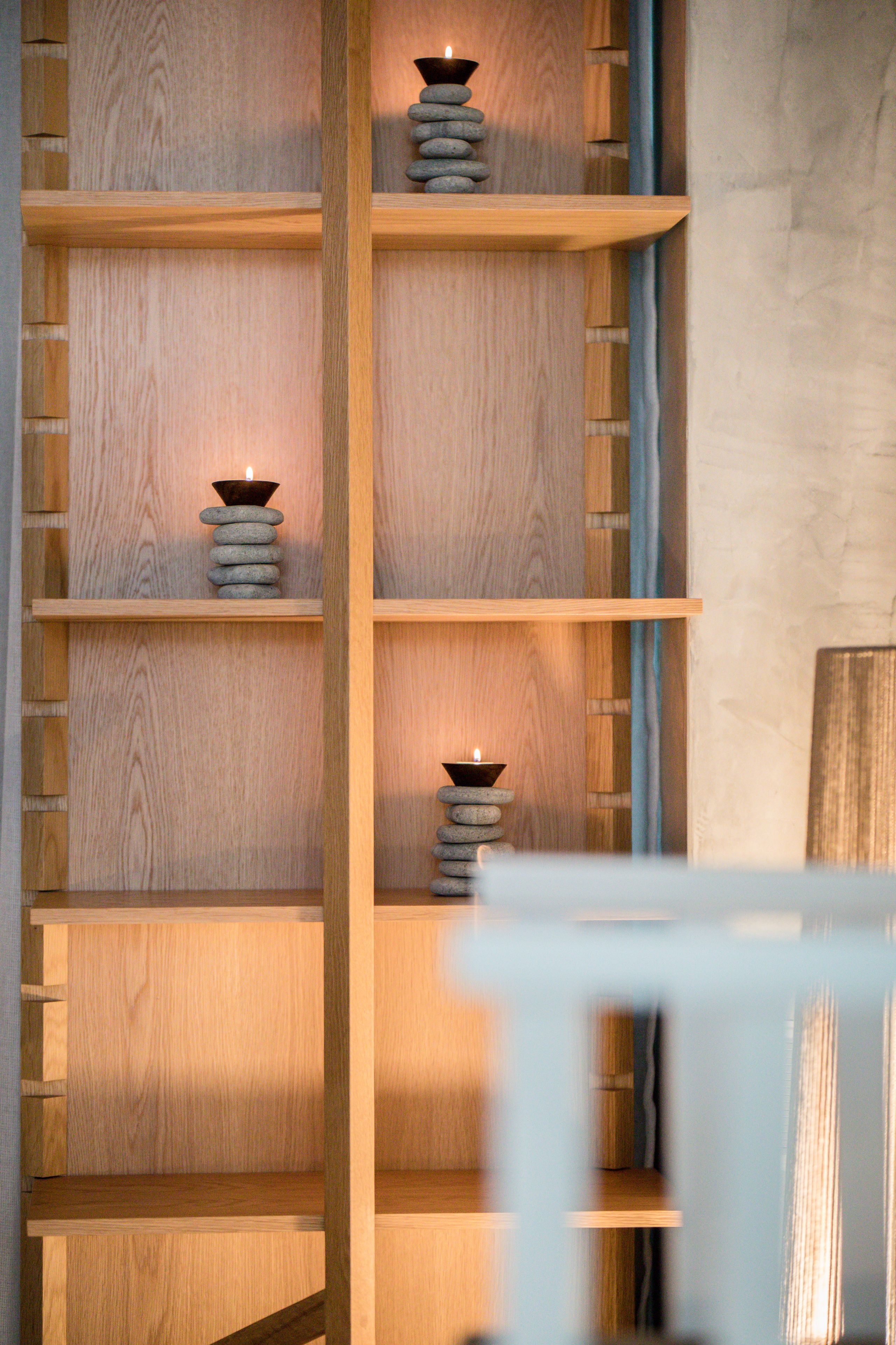 A wooden shelving unit with candles and stones.