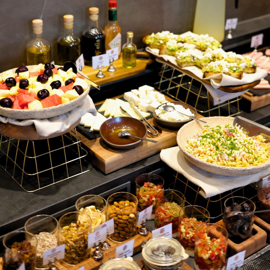 A buffet with various food items, including fruits, cheeses, and salads.