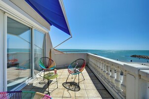 Un balcón con vistas al mar, que cuenta con una barandilla blanca y un toldo azul.