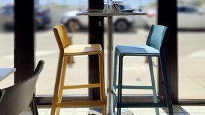 Een tafel met twee stoelen, met uitzicht op de parkeerplaats en een gebouw op de achtergrond.
