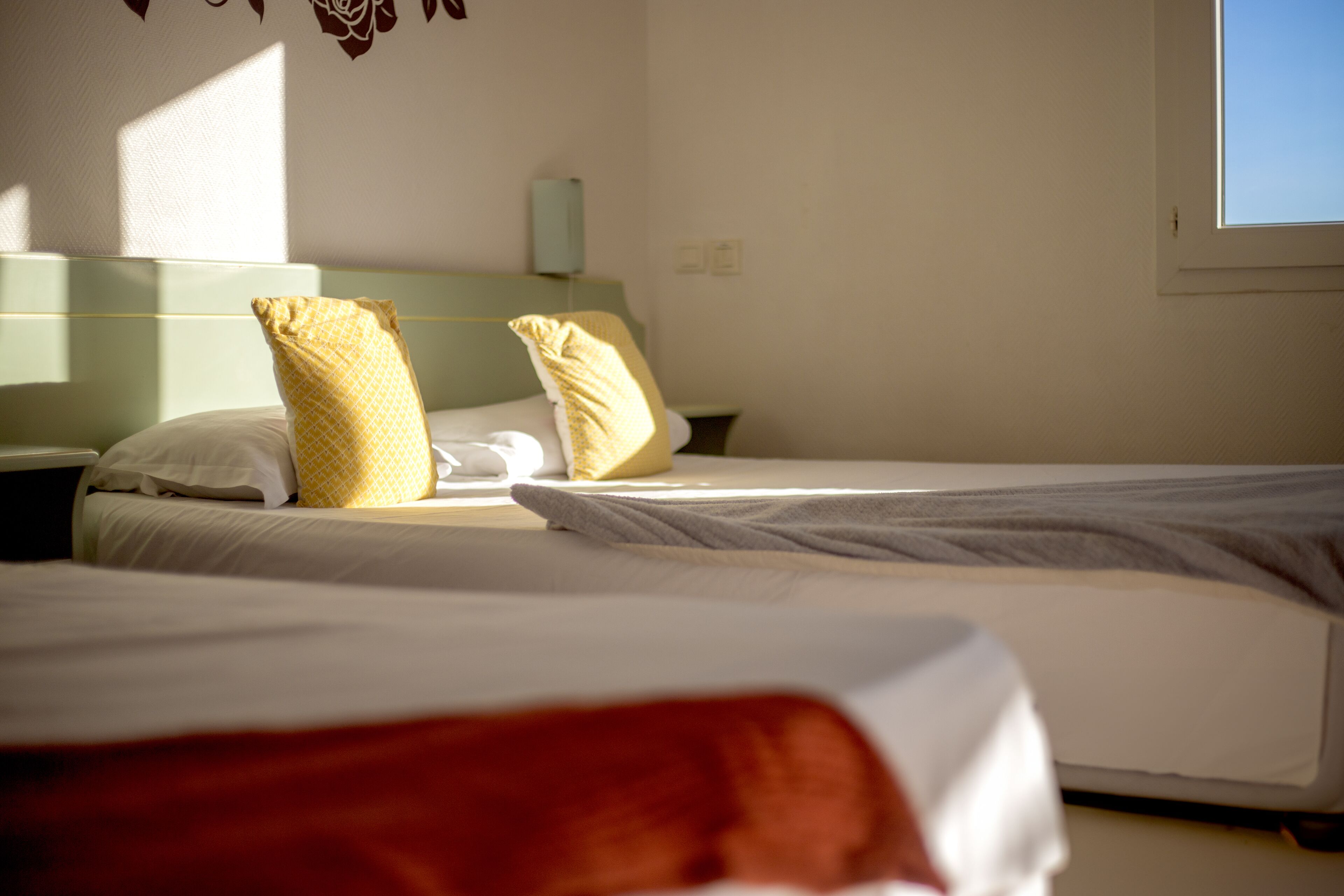A hotel room with two beds, a nightstand, and a window.
