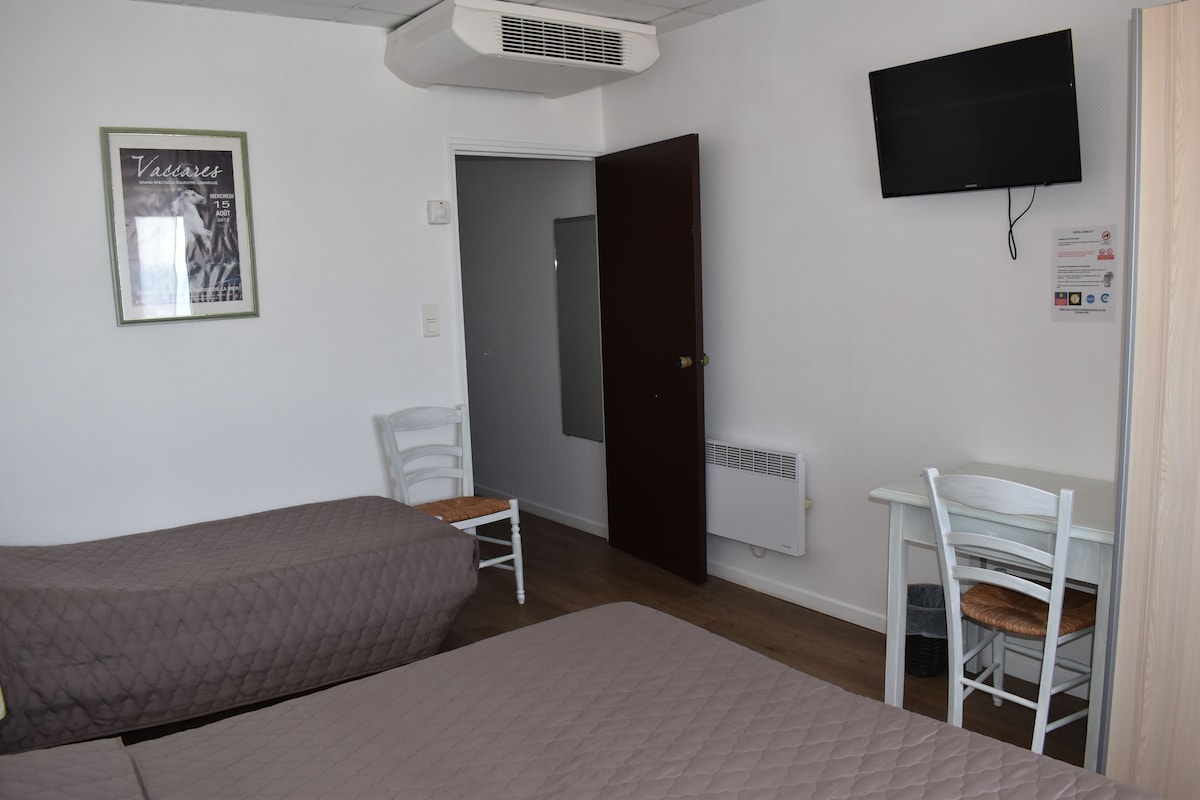 A room with a bed, a desk, a chair, a television, and a poster on the wall.