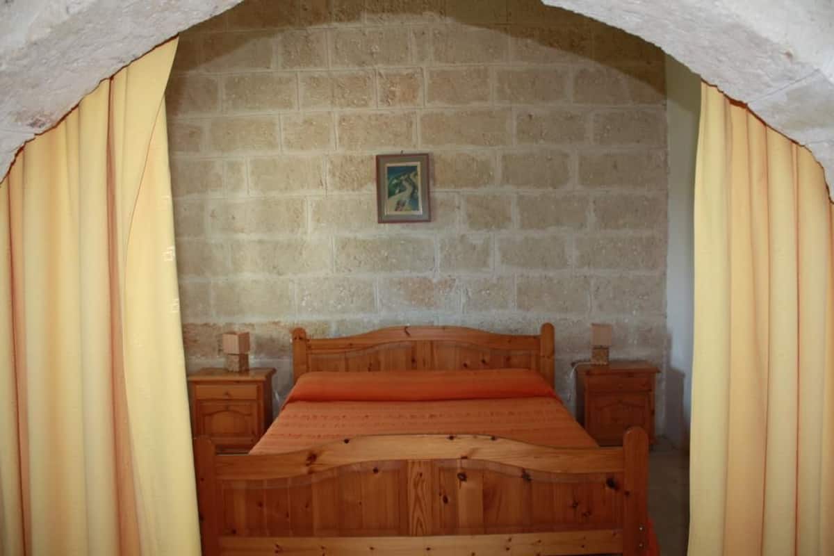 A bedroom with a wooden bed, two bedside tables, and a brick wall.
