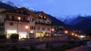 Un hotel con varios pisos, balcones y vistas a montañas nevadas al fondo.