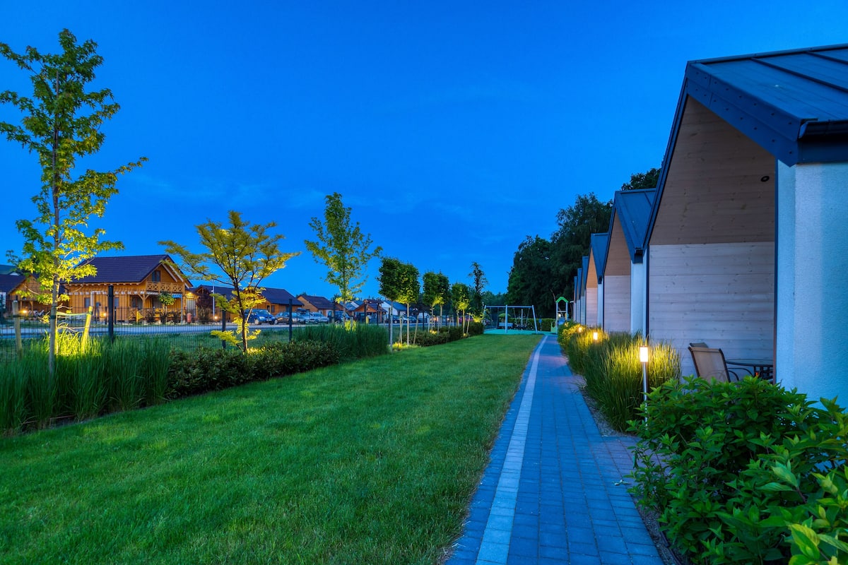 A pathway leading to a row of modern buildings with a well-maintained lawn and trees.
