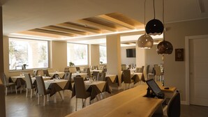 A spacious dining area with multiple tables and chairs, large windows, and a modern ceiling design. - La Perla (Camerano)