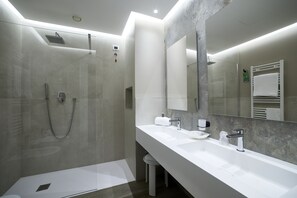 A modern bathroom with a glass-enclosed shower, a large mirror, and a white vanity with a sink and towel rack. - La Perla (Camerano)