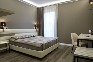A modern hotel room with a large bed, a desk, a chair, and a window with curtains. - La Perla (Camerano)