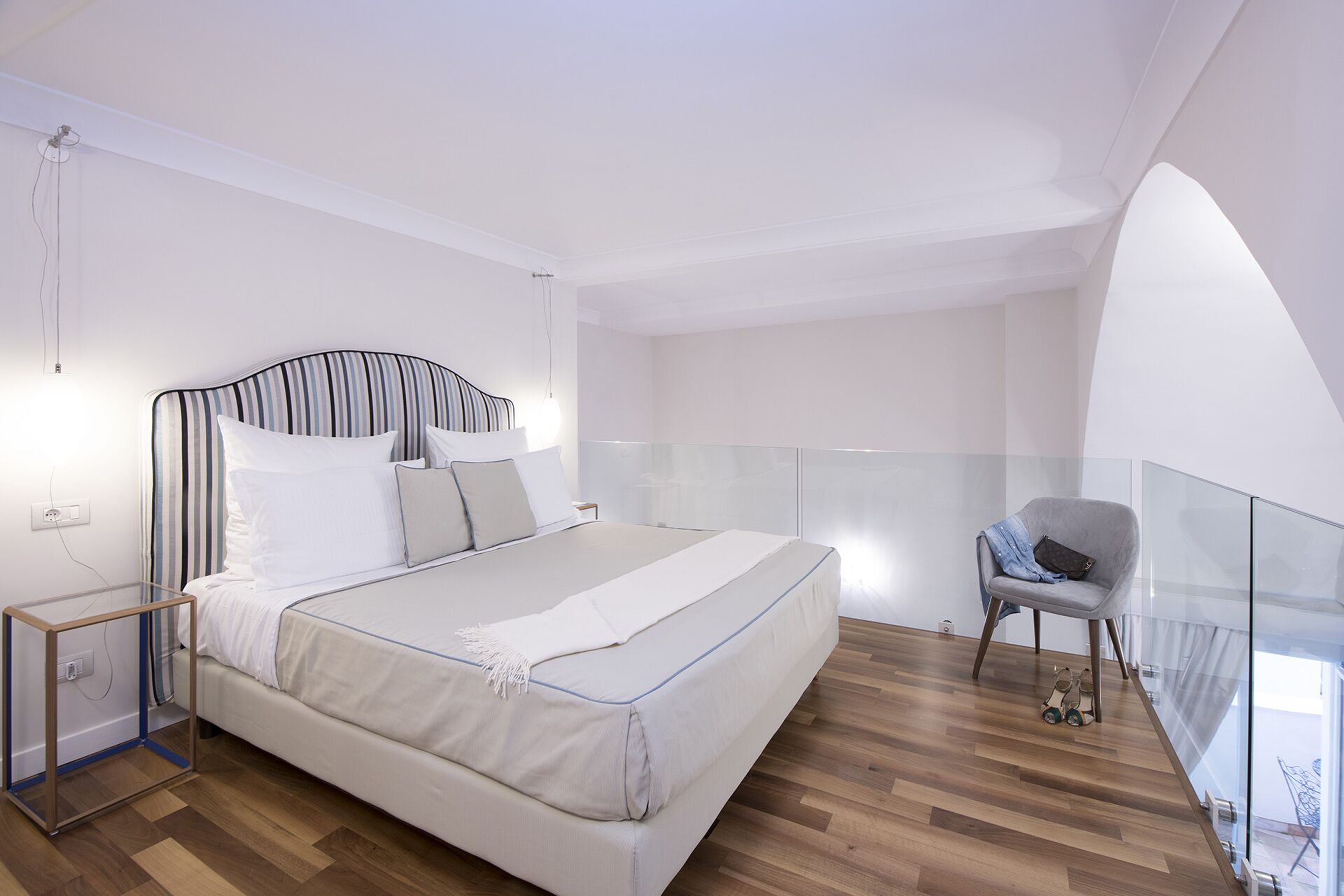 Ein modernes Schlafzimmer mit einem großen Bett, einer Glastrennwand und Blick ins Freie.