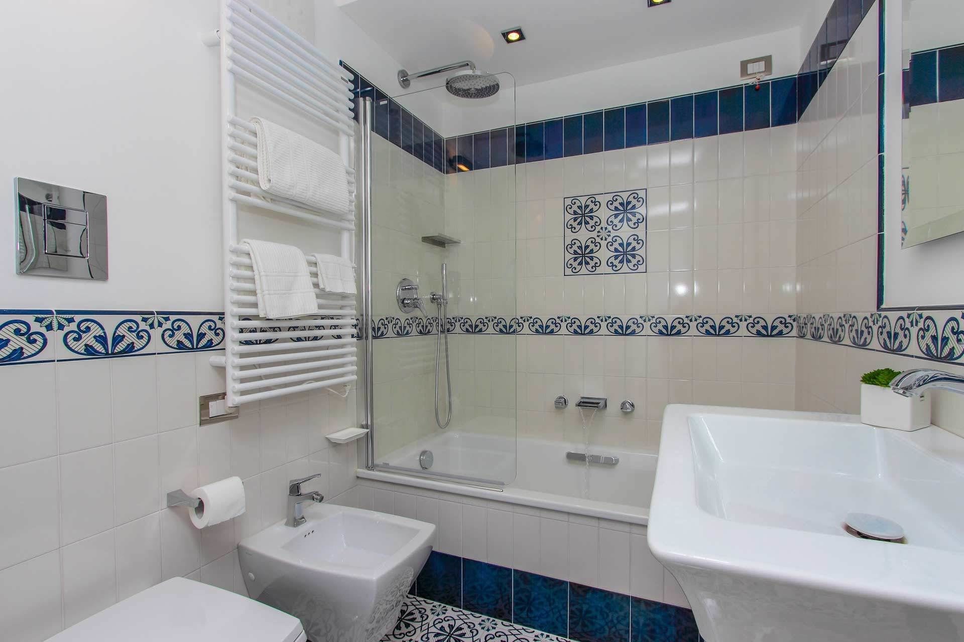 A bathroom with a glass-enclosed shower, a bidet, a sink, and a toilet.