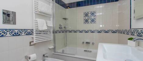 A bathroom with a glass-enclosed shower, a bidet, a sink, and a toilet.