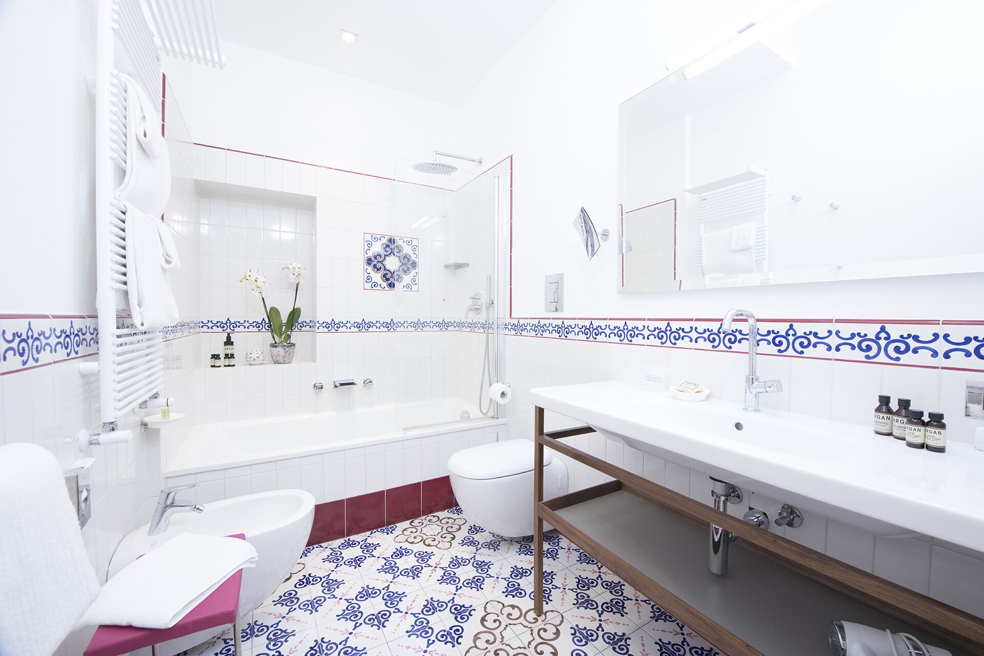 Une salle de bain moderne avec des carreaux blancs, un grand miroir, une baignoire, un lavabo et une douche.