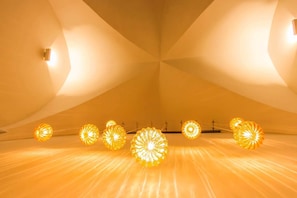 A room with a unique geometric ceiling design and a series of spherical light fixtures. - DieciSedici (Amalfi)