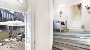 A modern interior with a staircase, a seating area with a sofa, and a dining setup with tables and chairs.